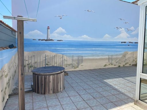Murale représentant une plage avec un phare au loin et des oiseaux en vol.