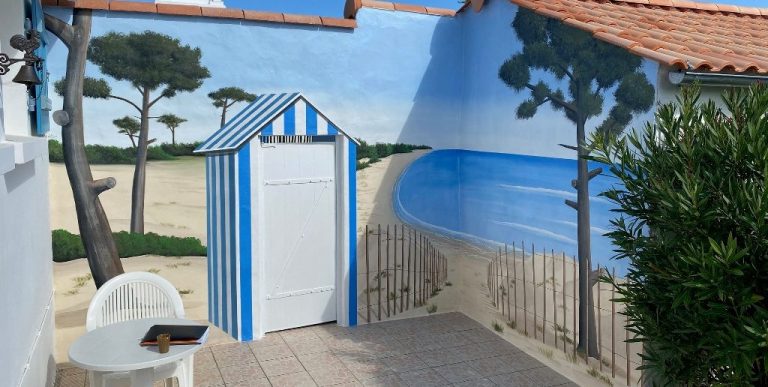 Fresque cabine de plage rayée bleue et blanche avec mur peint de plage et paysage marin.