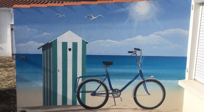 Fresque en trompe oeil vélo bleu devant une cabane de plage sur fond de mer et ciel ensoleillé.