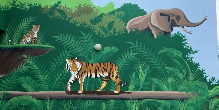 fresque murale d'un tigre marche sur une branche, tandis qu'un éléphant et un léopard se tiennent en arrière-plan.